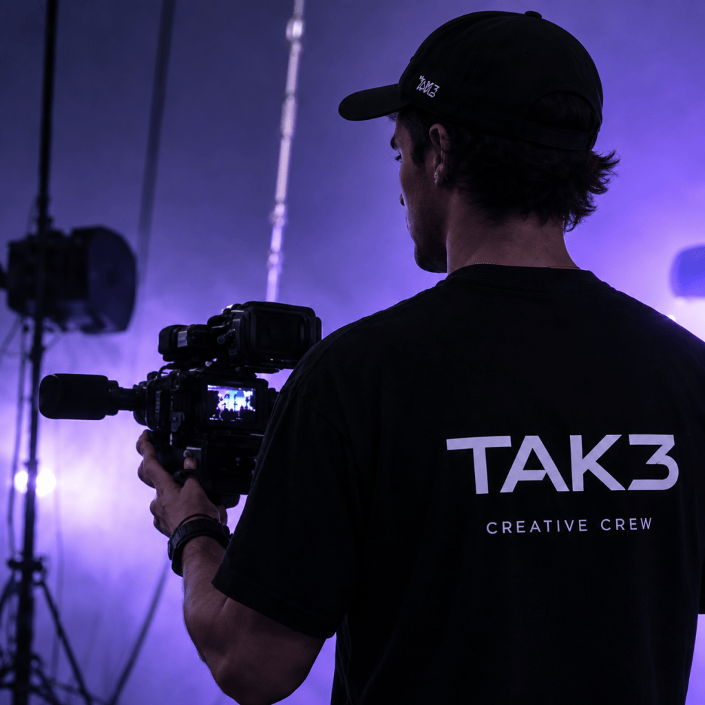Videógrafo de TAK3 grabando entre bastidores con iluminación violeta